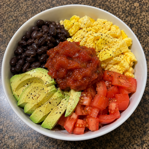 Breakfast bowl with scrambled eggs black beans avocado tomatoes and salsa