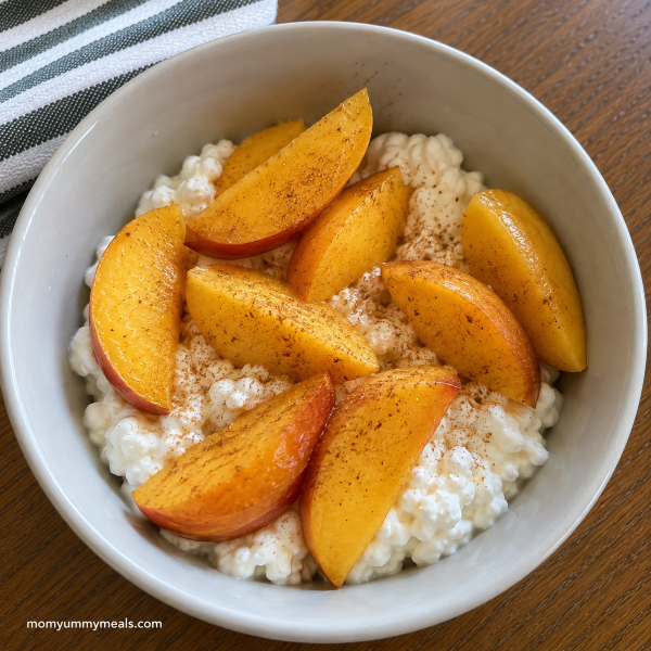 Cottage cheese snack bowl topped with fresh peaches and cinnamon