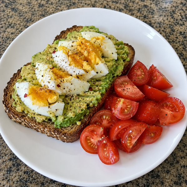 Egg and avocado toast on whole grain bread with fresh tomatoes