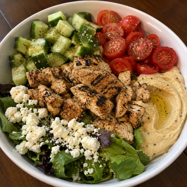 Greek chicken bowl with cucumber tomatoes hummus greens and feta