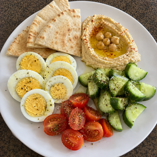 Mediterranean breakfast plate with hard boiled eggs hummus cucumber tomatoes and pita