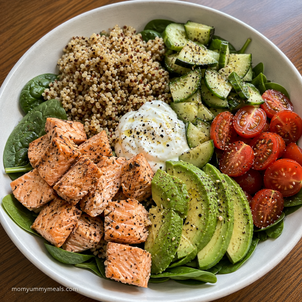 Salmon quinoa bowl with spinach cucumber tomatoes and avocado