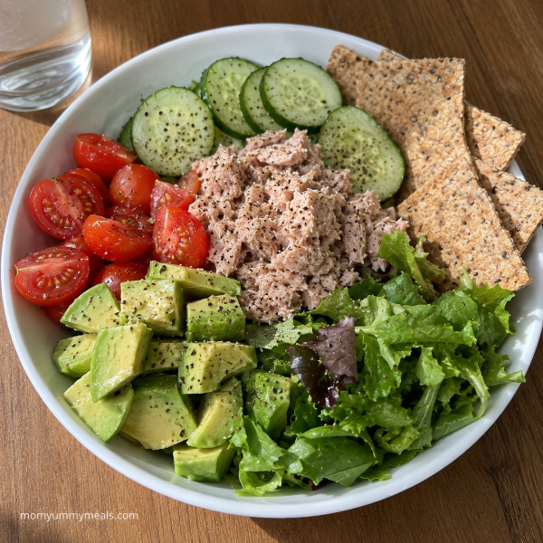 Tuna cucumber bowl with avocado tomatoes greens and whole grain crackers