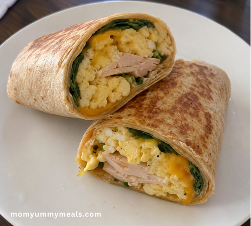 High protein breakfast wrap filled with scrambled eggs turkey cheese and spinach