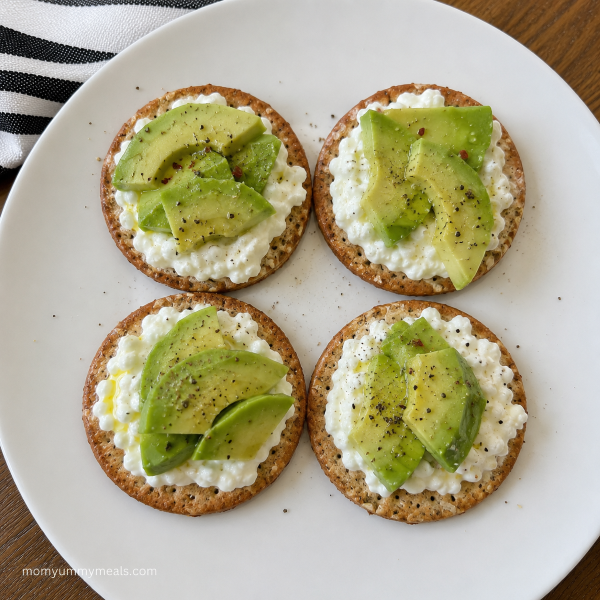 Whole grain crackers topped with cottage cheese and avocado